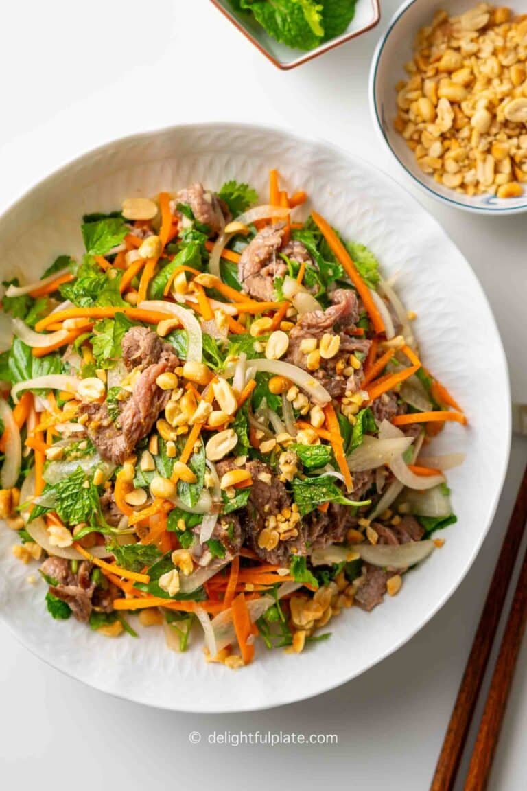 a plate of Vietnamese rare beef in lime juice salad (bo tai chanh) with extra roasted peanuts on the side.