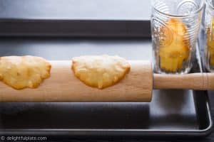 Place hot tuiles over a rolling pin to form their curved shape.