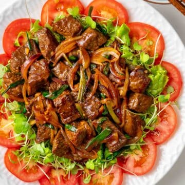 a plate of Vietnamese shaking beef (bo luc lac) with rice on the side.