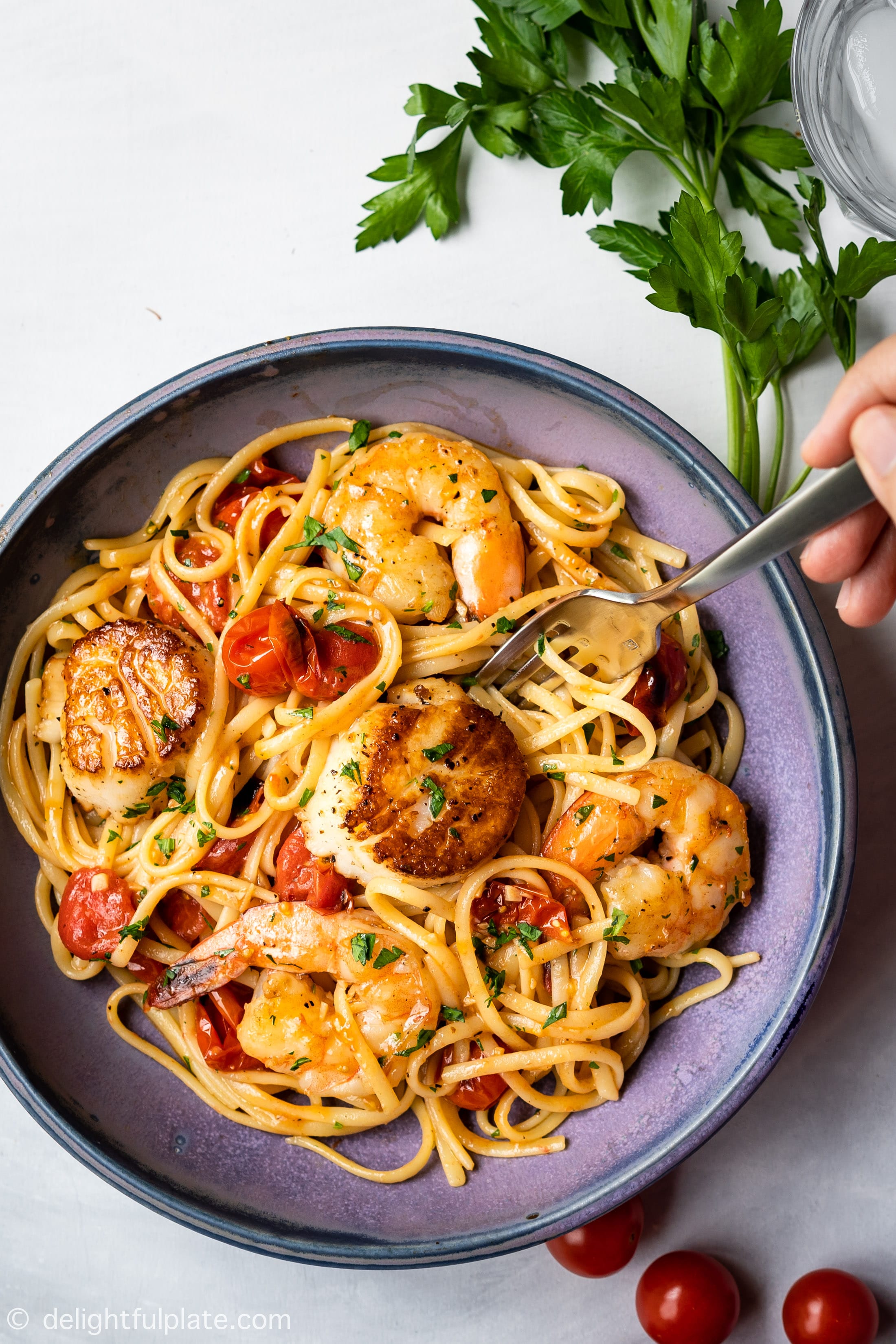 a plate of shrimp and scallop pasta with cherry tomatoes