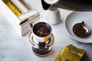 Brewing Vietnamese Coffee step-by-step: pouring hot water into the filter and let the coffee drip into the glass.