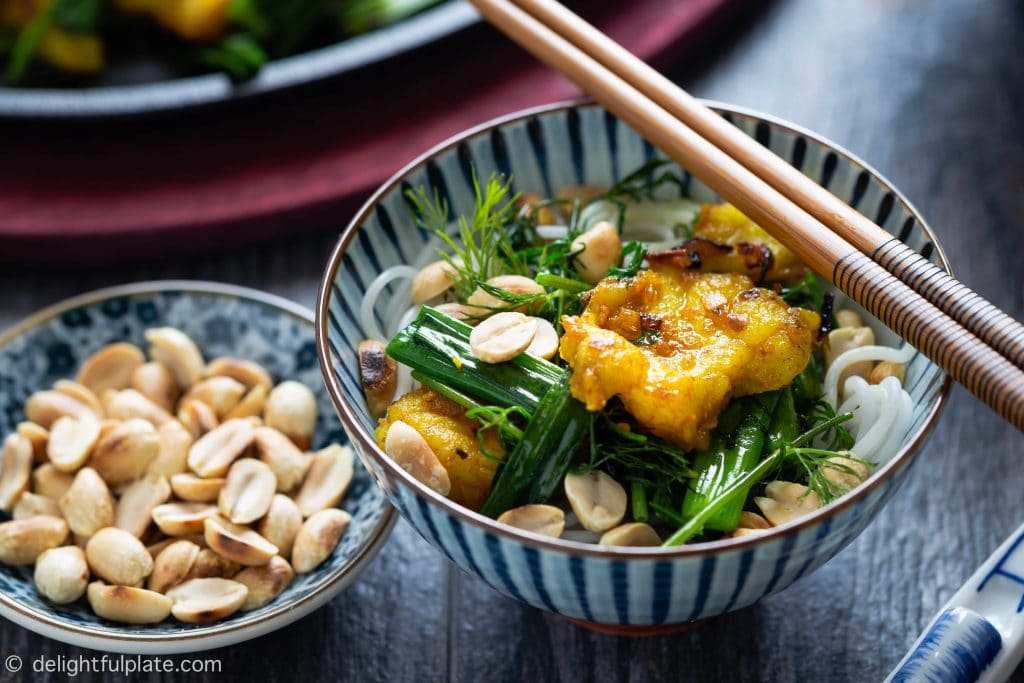 A bowl of Cha Ca Hanoi consists of melt-in-the-mouth grilled turmeric fish, cooked spring onion and dill, soft vermicelli noodles and crunchy roasted peanuts.