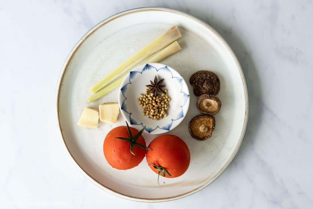 Ingredients for salmon noodle soup broth: lemongrass, ginger, tomato, dried shiitake mushrooms, star anise, coriander seeds