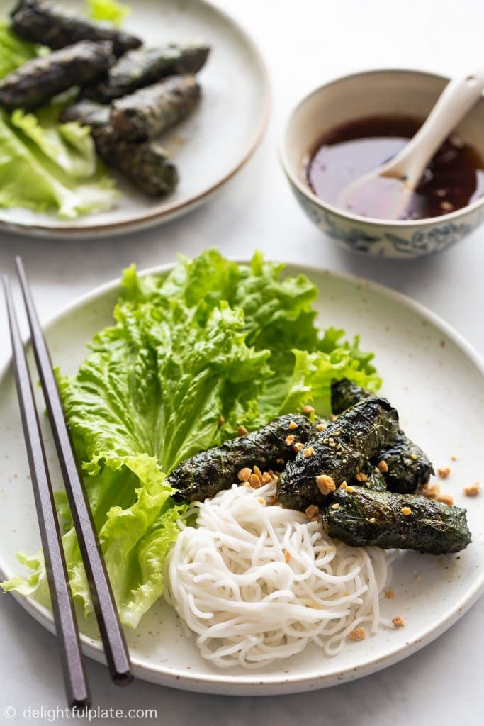 Vietnamese Grilled Beef in Wild Betel Leaves (Bo Nuong La Lot) is served with rice vermicelli noodles, lettuce, fresh herbs, roasted peanuts and sweet and sour dressing.