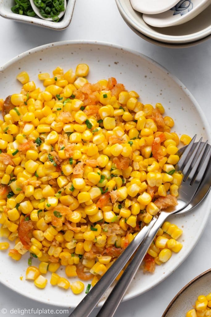 A plate of Sweet corn sautéed in butter with dried shrimps and scallions. Vietnamese Sautéed Corn with Dried Shrimps (Bap Xao) is a popular street food snack in Saigon.