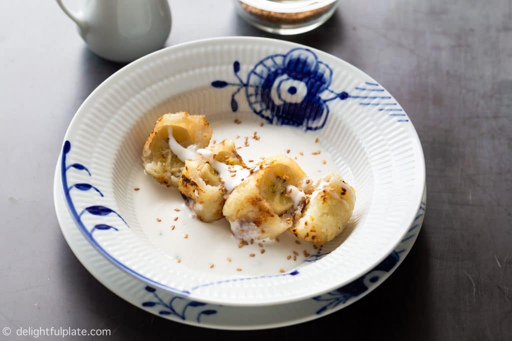 Grilled banana sticky rice rolls, served with coconut sauce and toasted sesame seeds. This is a popular Southern Vietnamese dessert.