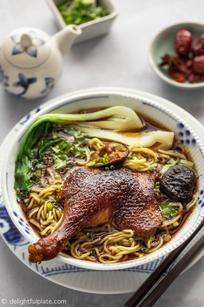 A bowl of Vietnamese Duck Noodle Soup (Mi Vit Tiem) featuring slippery noodles, fall-off-the-bone duck legs, and a dark broth.