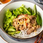 A bowl of Vietnamese noodle salad with stir-fried pork, beansprouts, lettuce and herbs