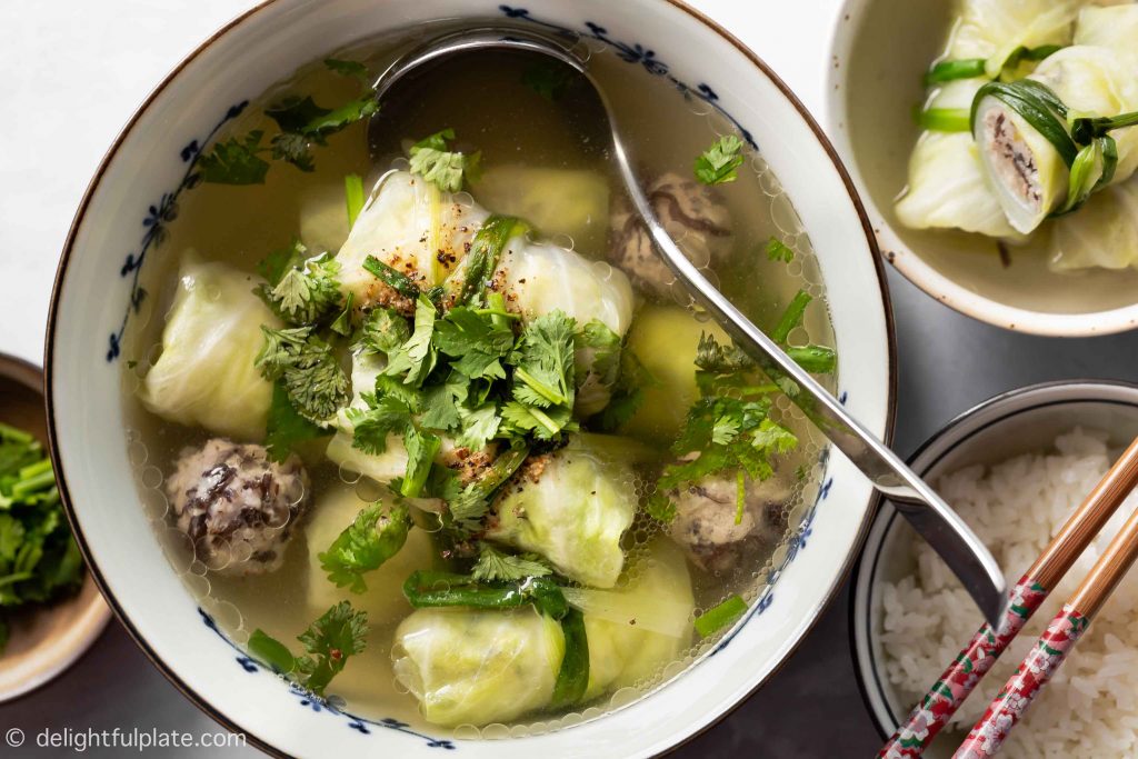 a bowl of pork cabbage roll soup, garnished with cilantro and served with rice