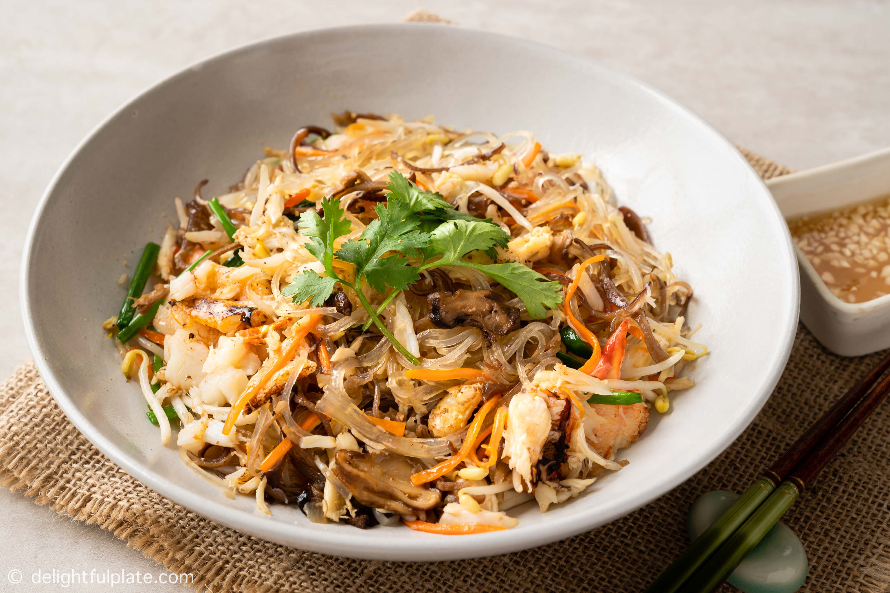 a bowl of stir-fried crab cellophane noodles (Mien Xao Cua), served with lime fish sauce dressing
