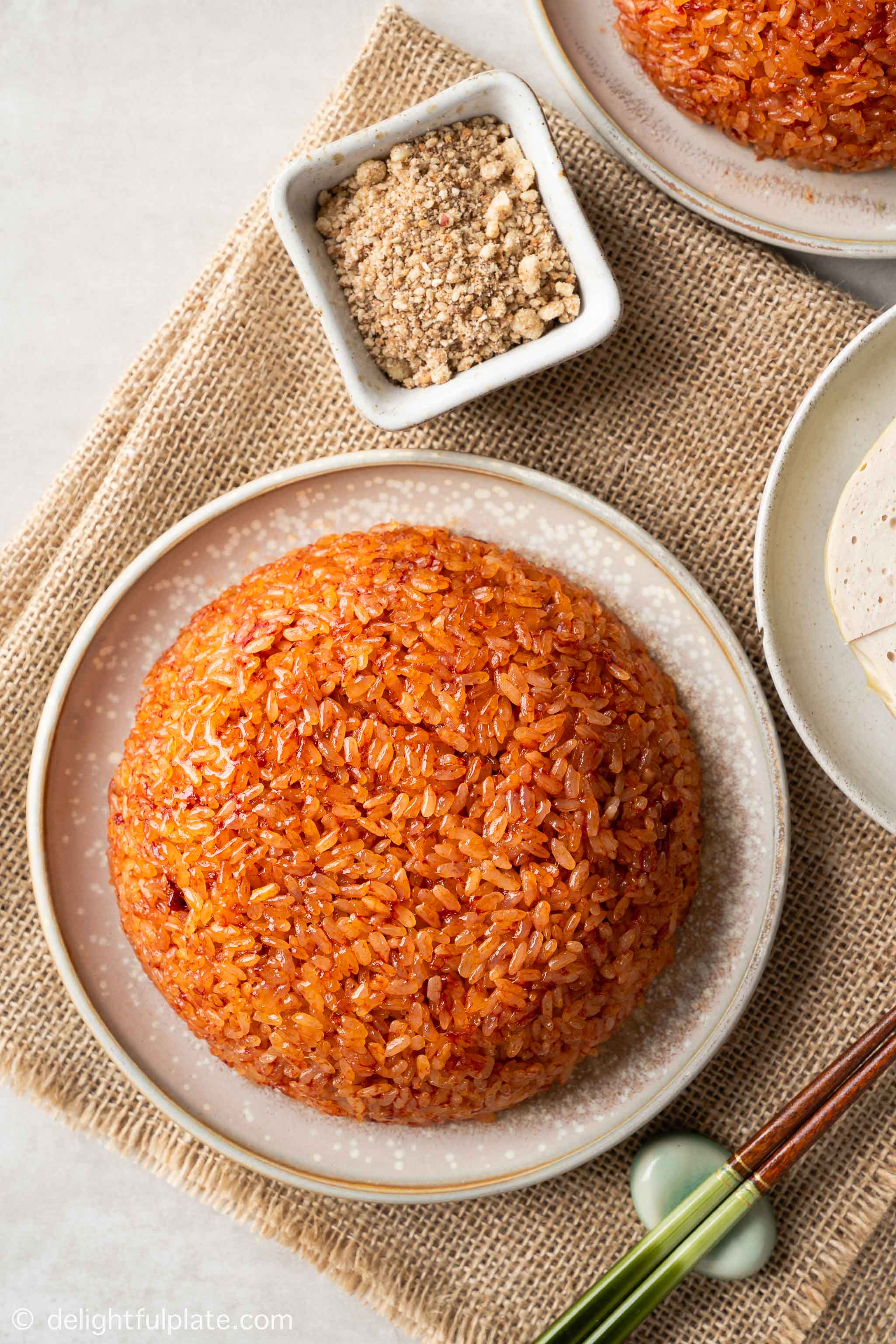 a plate of xoi gac (Vietnamese red sticky rice) served with Vietnamese ham.