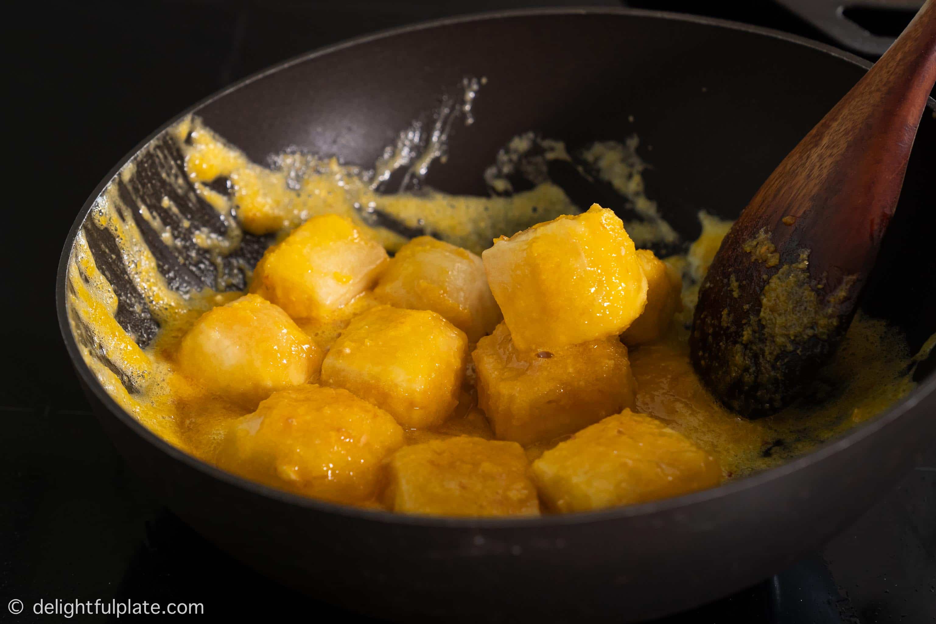 coating tofu with the salted egg sauce in a pan