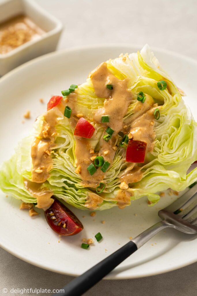 a wedge of iceberg lettuce served with peanut dressing