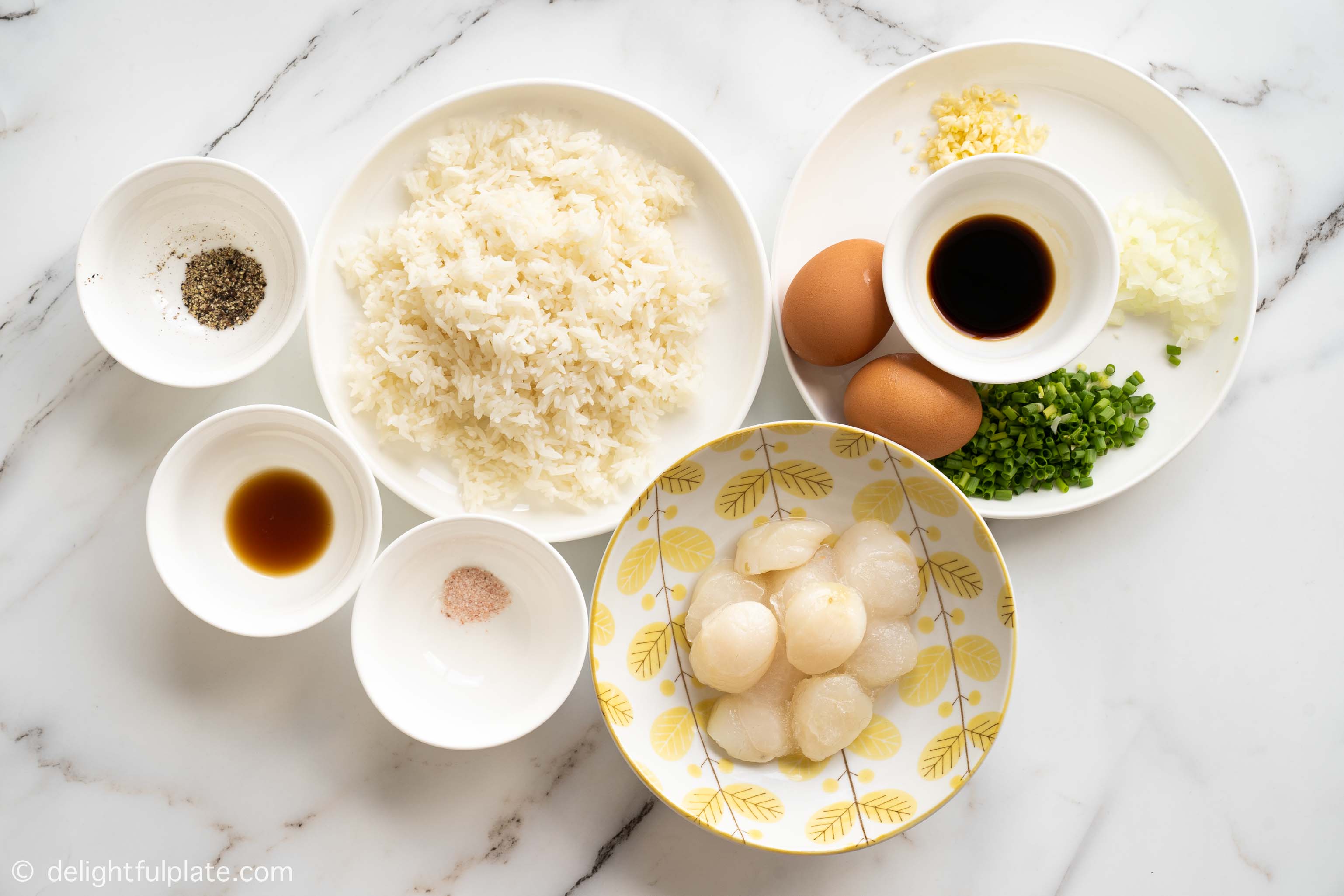 plates and bowls containing ingredients for scallop fried rice