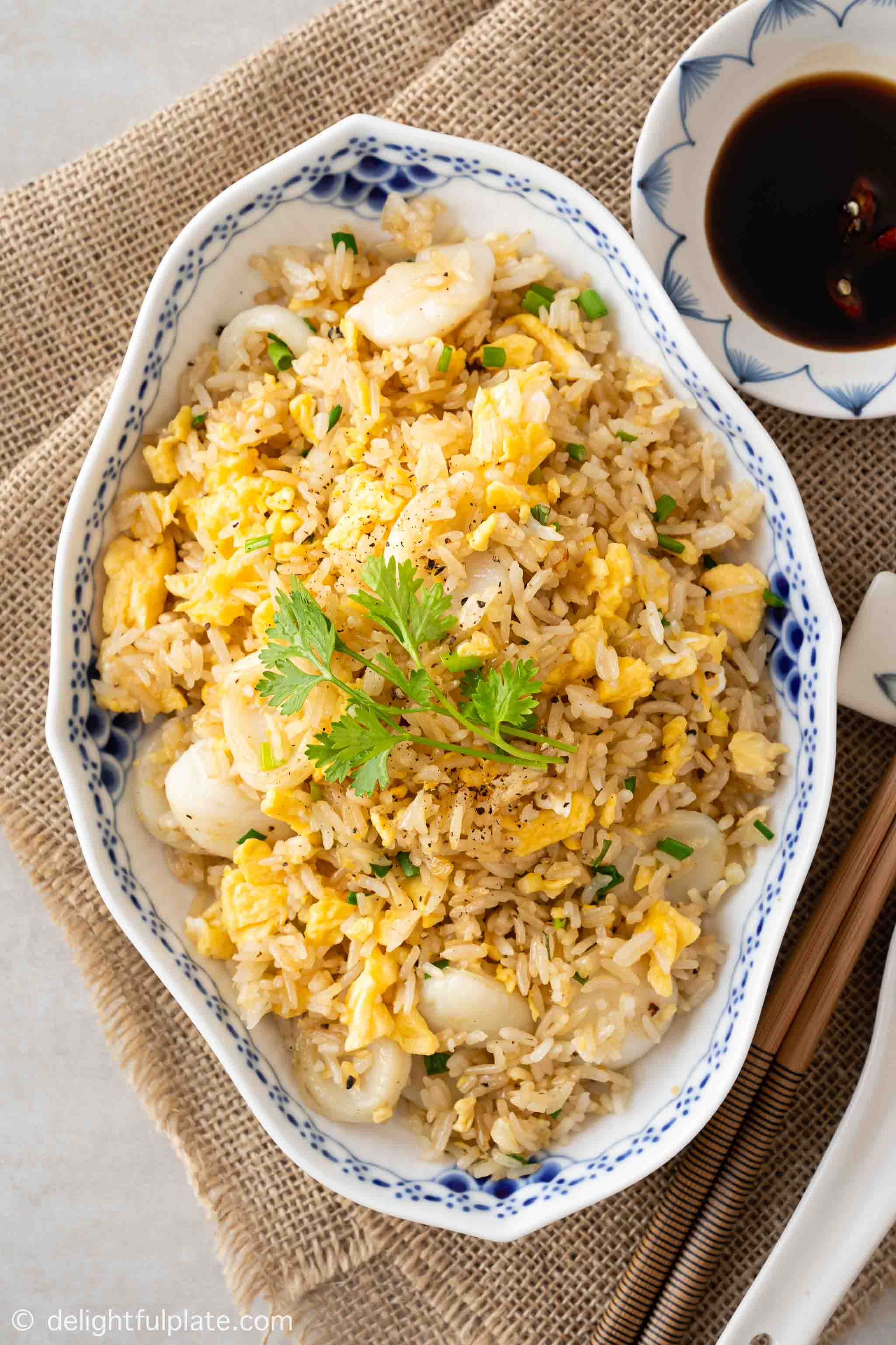 a plate of scallop fried rice with soy sauce on the side