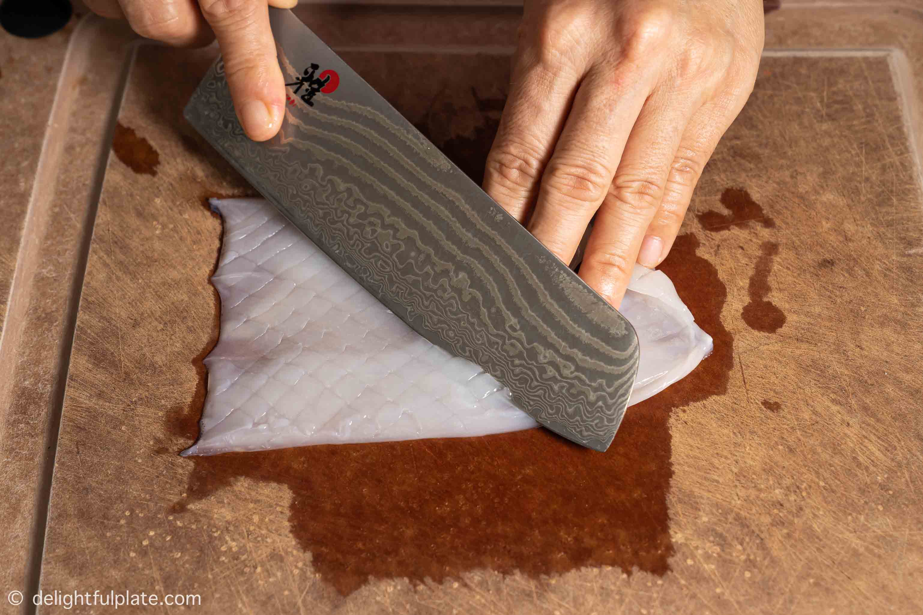 scoring squid on a cutting board