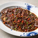a braised whole fish in Lao Gan Ma sauce on a plate