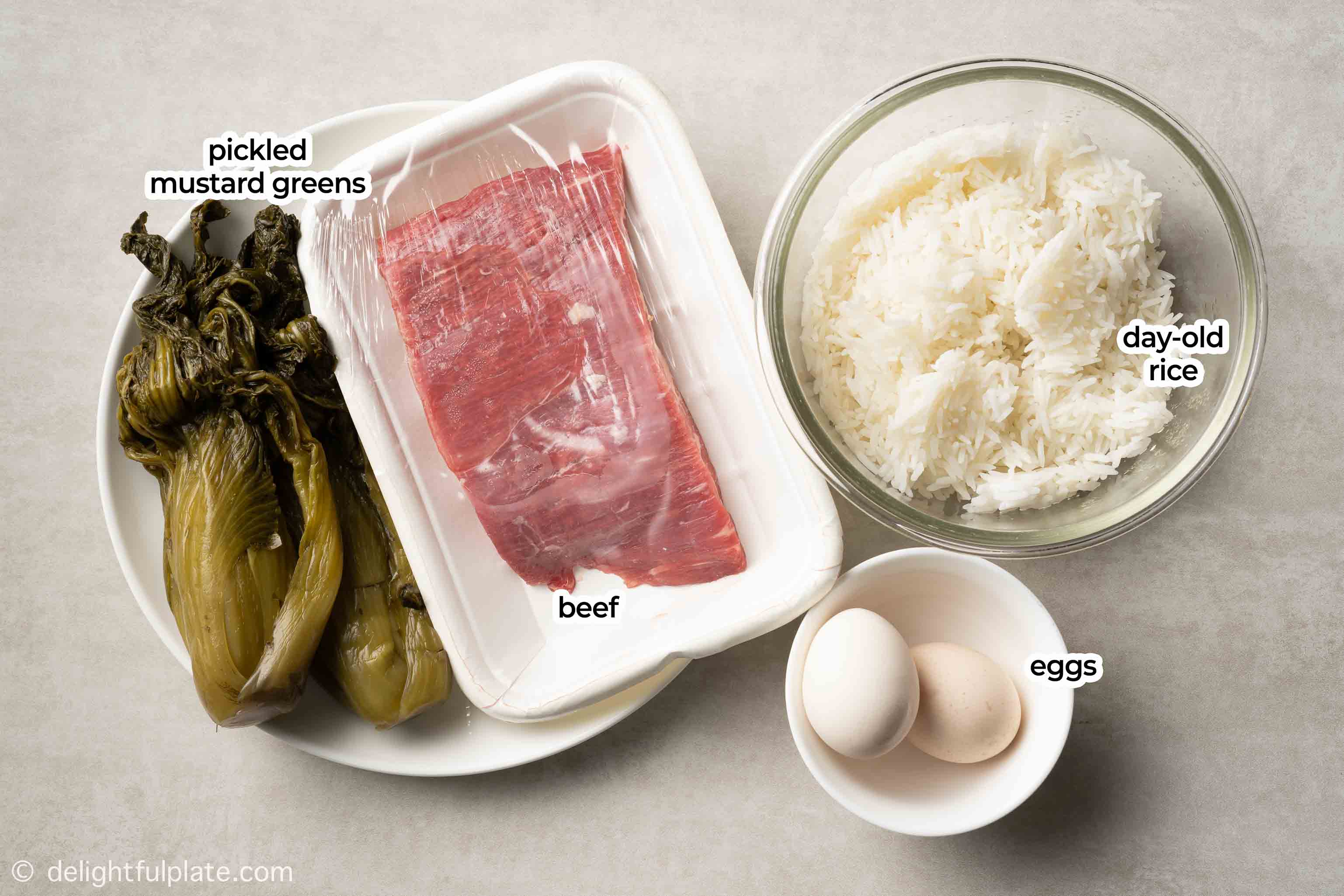 plates with ingredients for the fried rice: rice, beef, pickled mustard greens and eggs