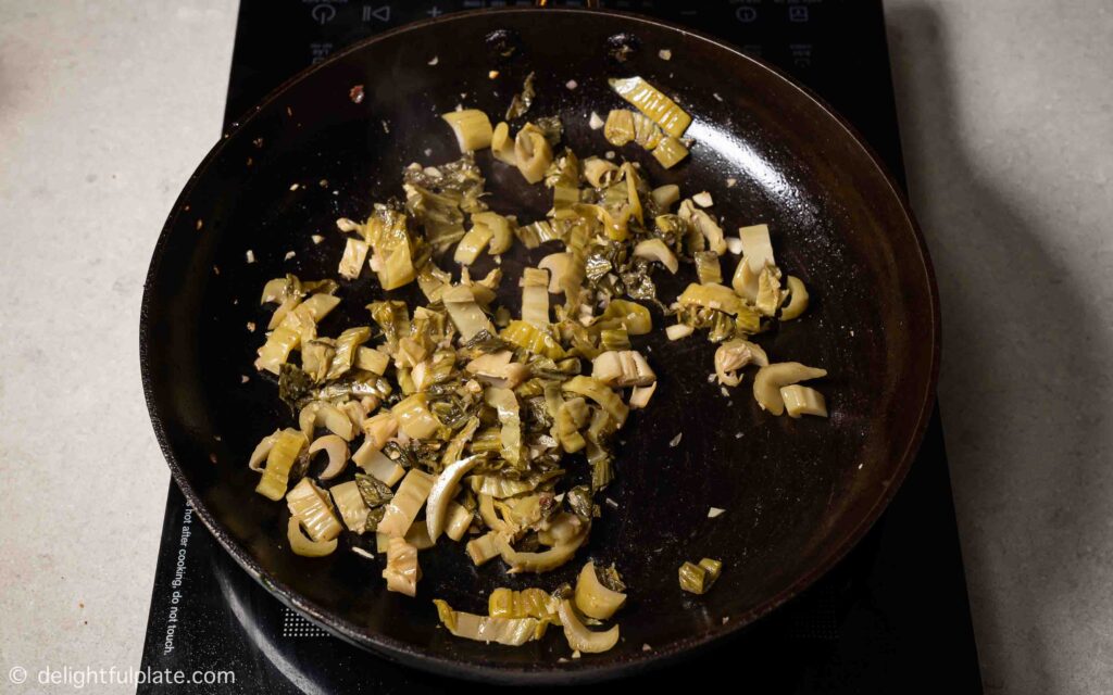 Sautéing pickled mustard greens in a pan