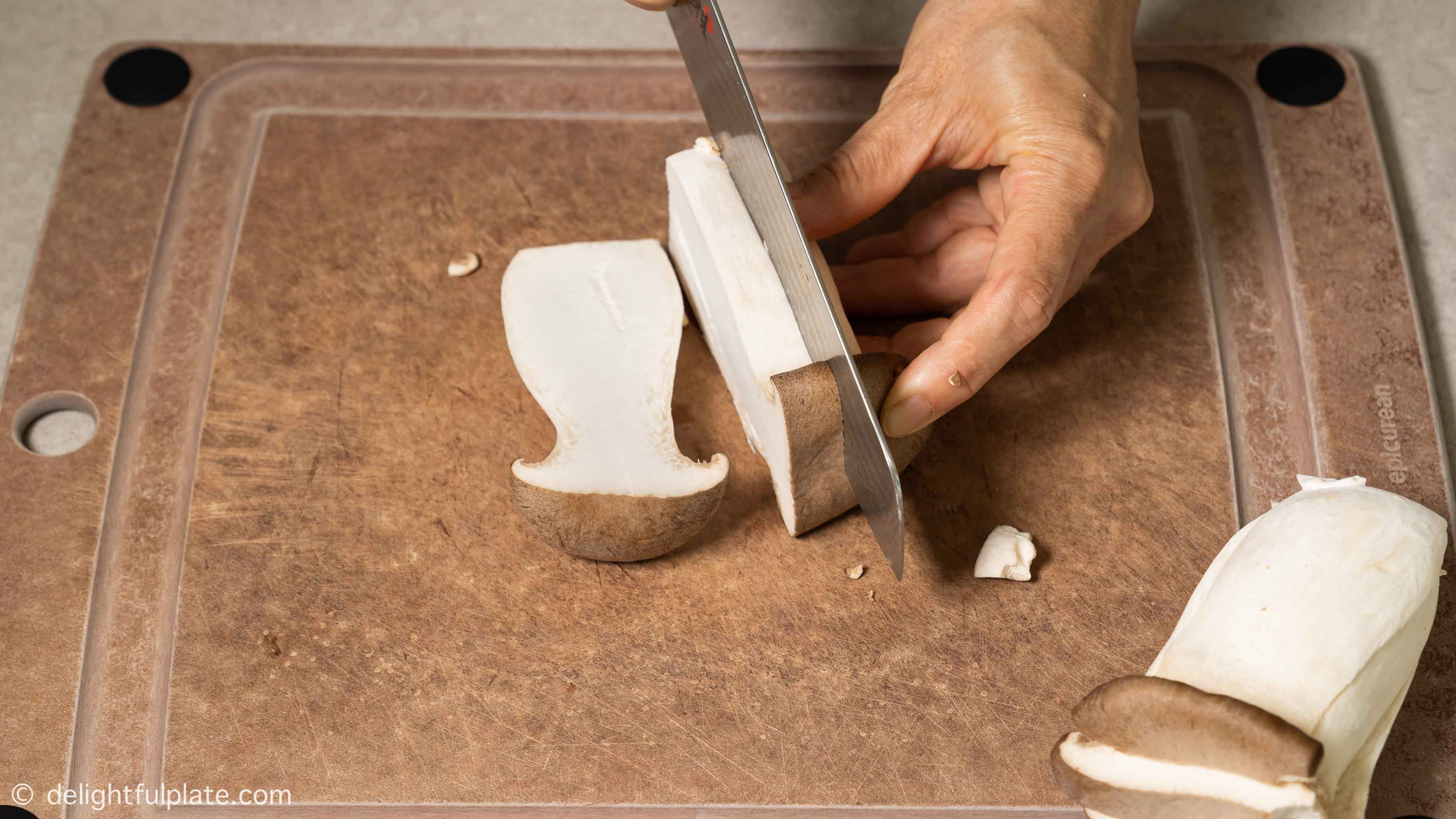 slicing king oyster mushrooms on a cutting board