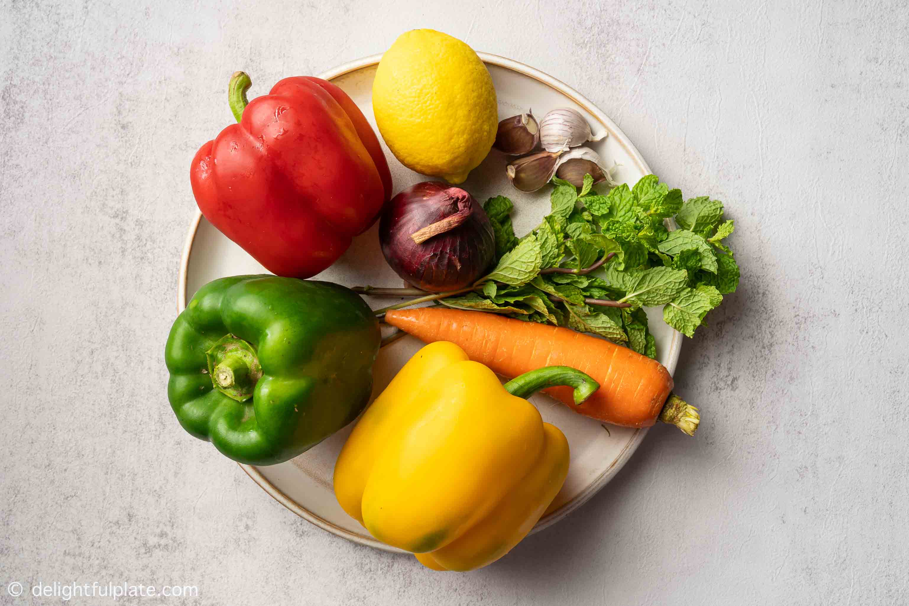 a plate containing bell pepper, carrot, onion and mint