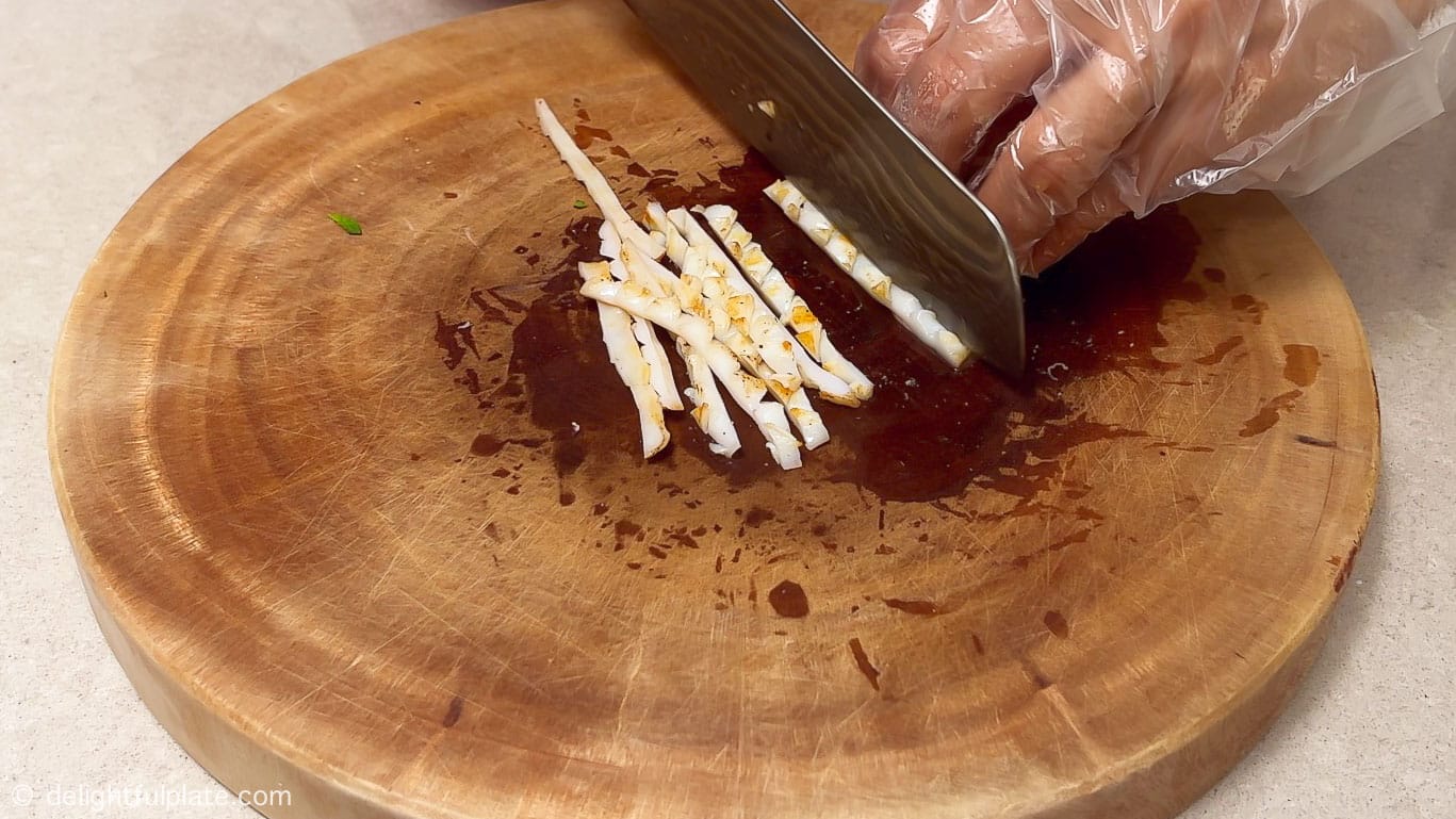 slicing grilled squid into thin strips