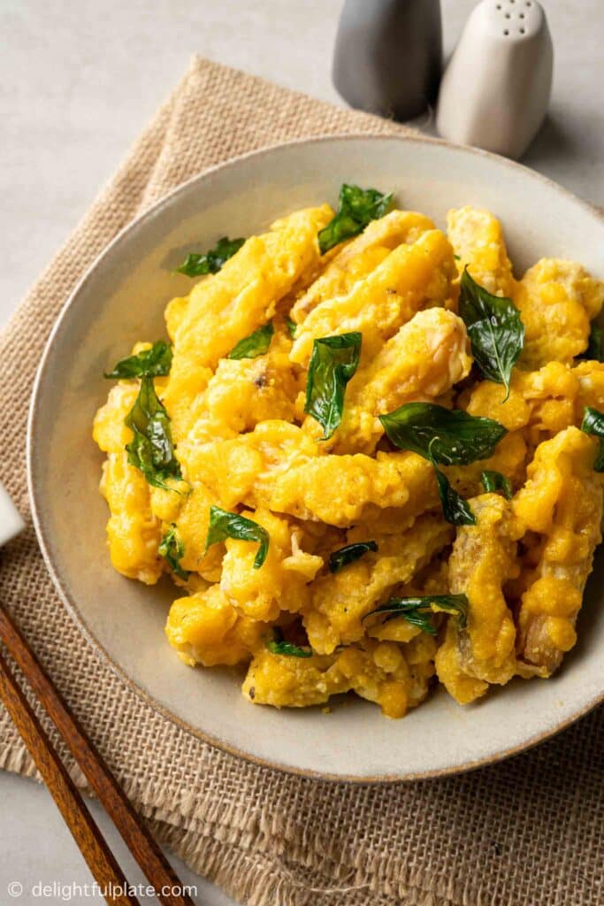 a plate of fried pumpkin fritters with salted egg sauce