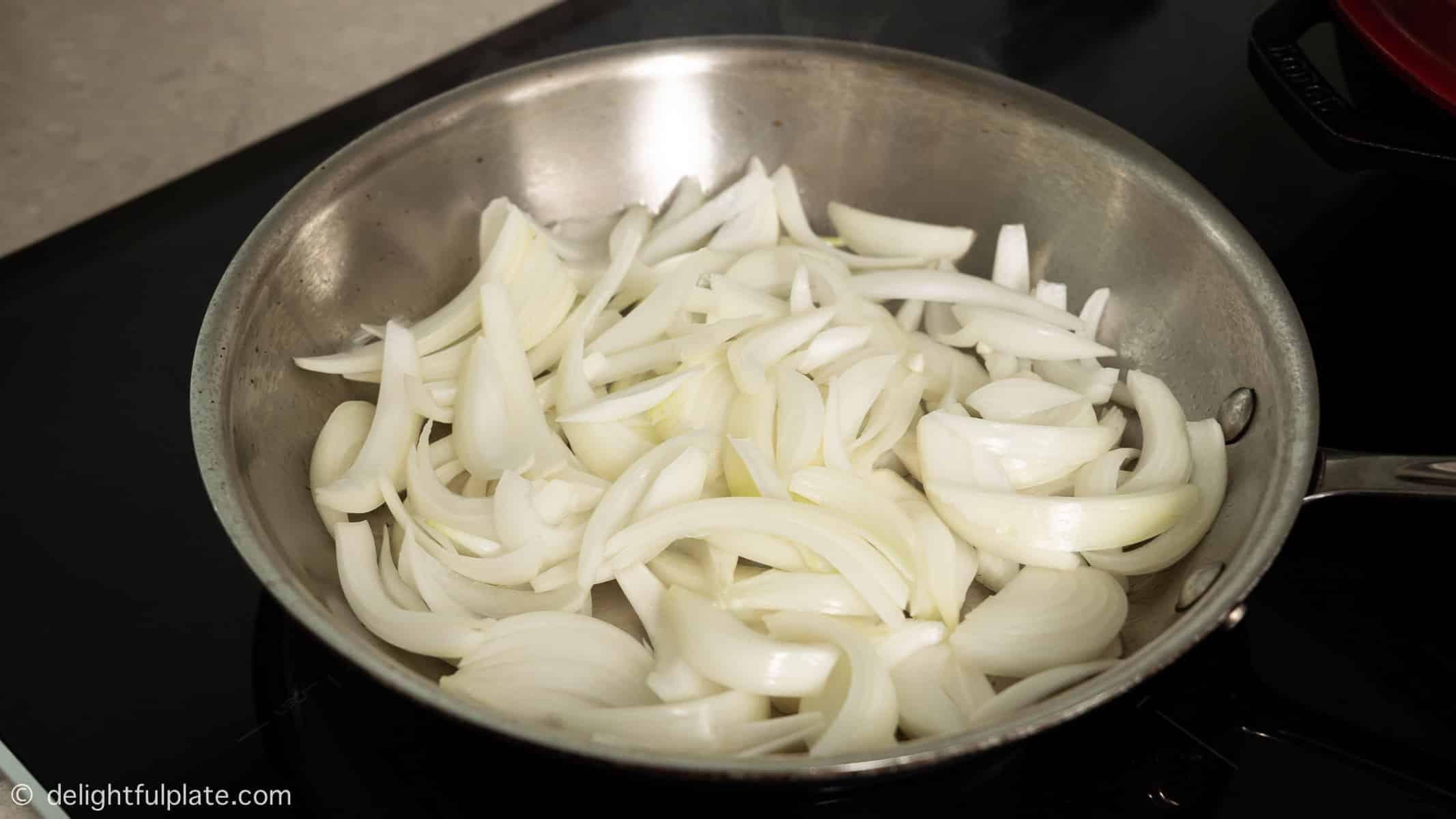 adding onion slices to a skillet