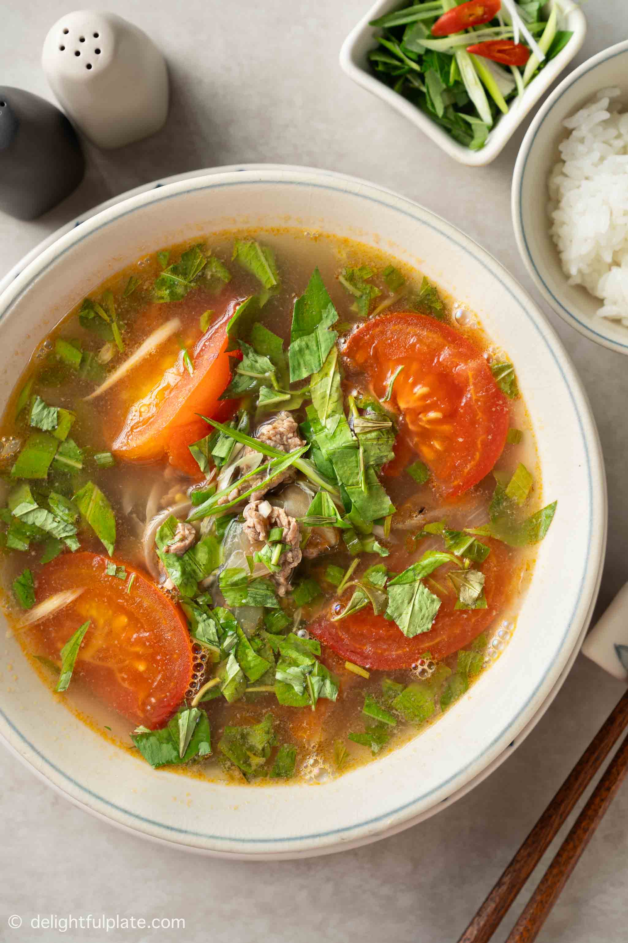 a bowl of Vietnamese tomato beef soup with coriander.